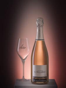 Mise en scène élégante d'une bouteille de Champagne Christophe Collard Premier Cru Brut et verre à vin, éclairage chaleureux en arrière-plan, par SL-photographie.