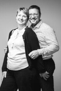 Image de SL-Photographie d'un couple en noir et blanc, souriant avec les bras autour de l'autre, l'homme en chemise à motifs et la femme en haut blanc, dans un studio à Courtisols.