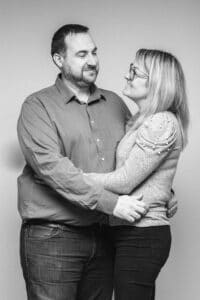 Portrait par SL-Photographie d'un couple, l'homme en chemise kaki et la femme en pull pailleté, échangeant un regard amoureux en noir et blanc dans un studio à Courtisols.