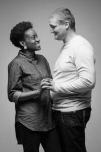 Photo en noir et blanc par SL-Photographie d'un couple intime, l'homme en sweat à col rond et la femme en chemisier gris, se regardant tendrement dans un studio à Courtisols.
