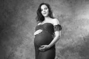 Élégante maternité en noir et blanc, femme enceinte tenant son ventre dans une pose gracieuse, immortalisée par SL-Photographie à Châlons-en-Champagne